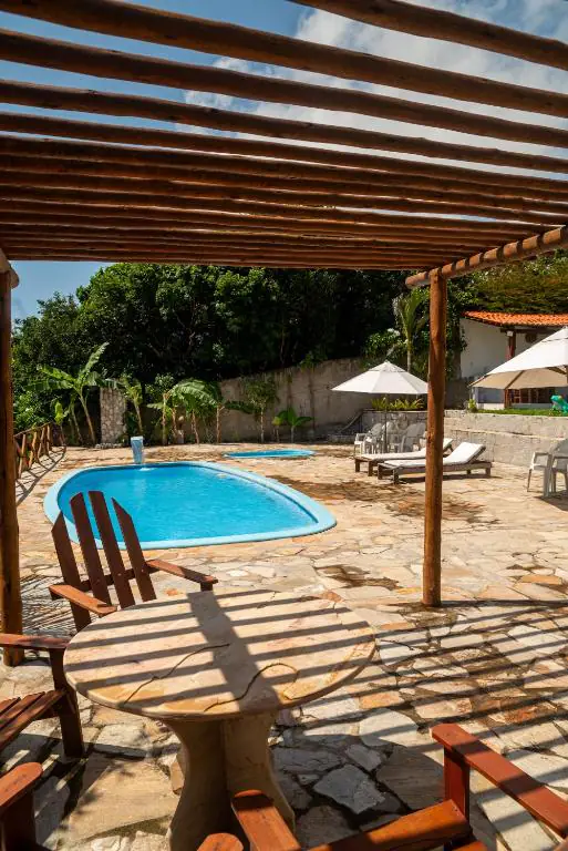 Deck da piscina visto do pergolado de madeira