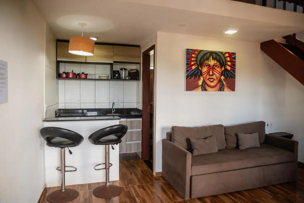 Sala da suíte com sofá e cozinha americana